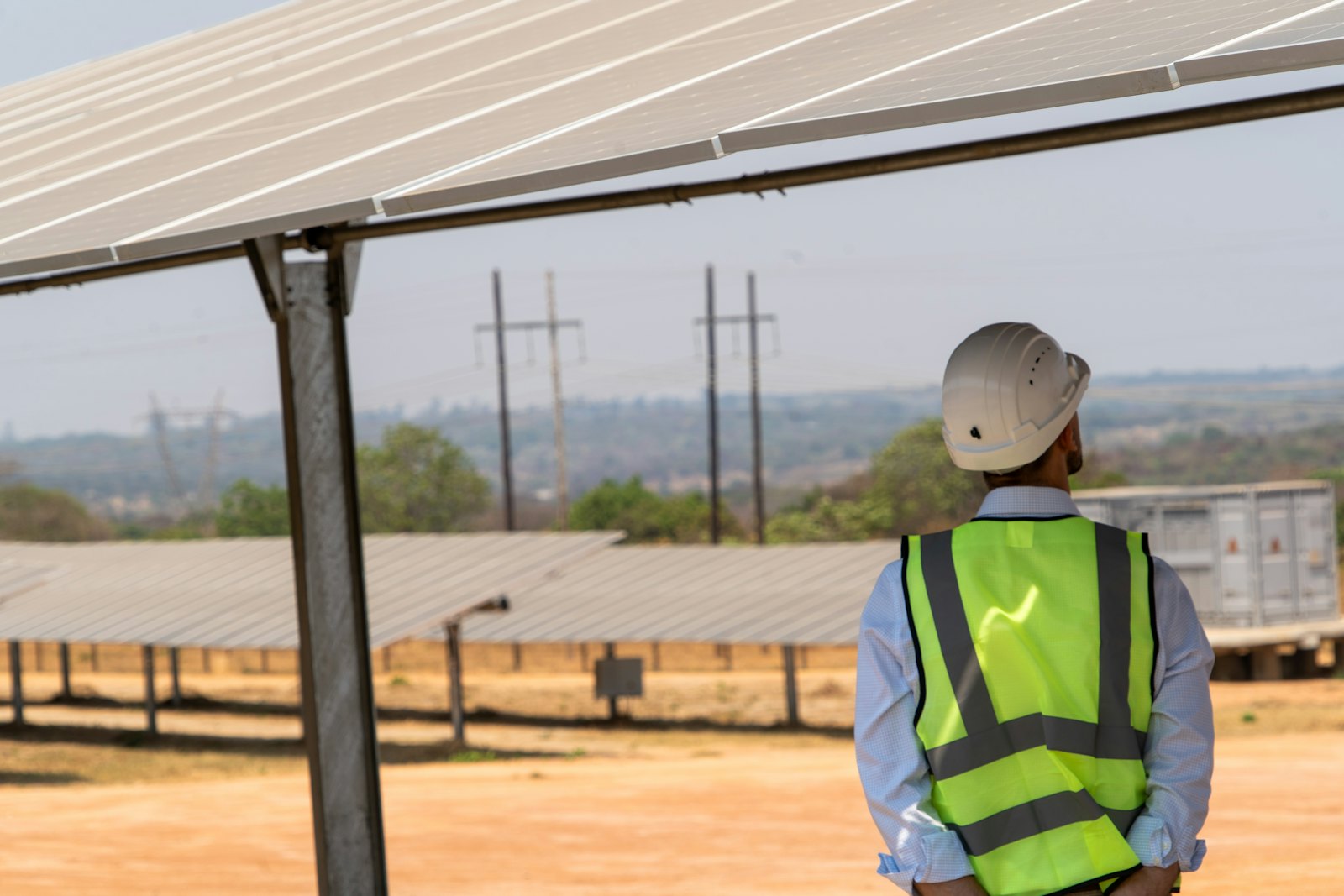 A worker in a safety vest at a solar farm